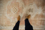 Distressed Oushak rug showing even, short pile with muted ivory, copper blush tones.