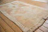 Distressed Turkish Oushak rug featuring an abrashed ivory field and distinct wave border.