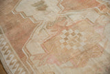 Distressed vintage Oushak rug close-up showing abrashed field, ivory, and dusty copper.