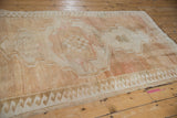 Vintage Oushak rug's reciprocating wave border, distressed pile in pale coffee bronze and ivory.
