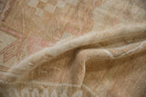 Textured pile of a distressed vintage Oushak rug in muted ivory, blush, and coffee tones.