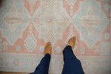 Distressed Oushak rug with even wear, featuring pale mint and cantaloupe geometric motifs underfoot.