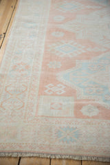 Distressed vintage Oushak rug corner, cantaloupe, mint, ivory geometric design and fringe.