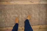 Distressed vintage Afghani Bokhara rug runner with beige elephant guls and pale pink accents.