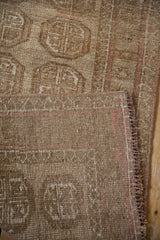 Distressed Afghani Bokhara runner detail, muted beige guls, faint pink hues, and secured selvage.