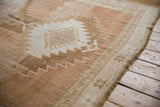 Distressed Oushak rug detail showing serrated medallion, starburst border, and time-softened abrash.
