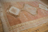 Distressed Oushak rug corner detail with abrashed apricot and blush tones, serrated motif, and patterned borders.