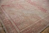 Distressed vintage Shiraz carpet with faded blush pink geometric blossoms and visible knot heads.