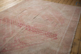 Faded blush geometric blossoms on distressed vintage Shiraz carpet, with visible knot head wear.