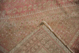 Distressed pink and beige vintage Shiraz rug pile revealing faint foundation and fringe.