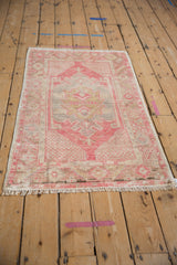 Distressed Oushak rug detail showing worn pink geometric motifs and intact side selvage.