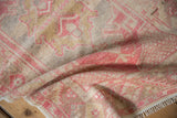Vintage distressed Oushak rug close-up, with faded pink geometric patterns and soft, worn texture.