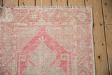 Distressed pink and ivory geometric floral corner of vintage Oushak rug, with fringe.