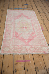 Distressed Oushak runner's center medallion, with geometric floral cross-sections in dust raspberry and ivory.