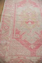 Distressed Oushak rug showing faded dust raspberry and ivory geometric motifs.