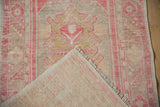 Distressed Oushak runner pile in dust raspberry and gold tones, showing woven foundation.