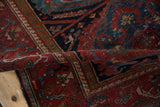 Folded section of vintage Mehreban rug displays raspberry red pile and blue floral contouring.