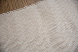 Natural undyed organic cotton rag rug, close-up of soft woven texture and clean edge.
