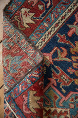 Hand-knotted Vintage Karaja rug folded, revealing its red, navy geometric patterns and woven foundation.