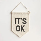 Handmade natural unbleached cotton banner with soft raised black 'IT'S OK' text, 8.5x16 inches.