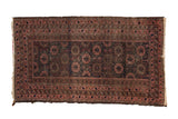 Hand knotted vintage Belouch rug with floral field, geometric borders in navy, dusty raspberry, and brown.