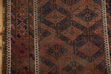 Close-up vintage Belouch rug: geometric guls in navy, madder red, brown, visible knot heads, goat hair selvage.