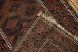 Repeating diamond guls in madder red, navy, and original goat hair selvage on vintage Belouch rug.