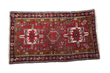 Vintage Persian Karaja rug with triple geometric medallions on a cherry red field and a navy starburst border.