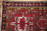 Corner of a vintage Persian Karaja rug with a navy starburst palmette border and saffron gold accents.