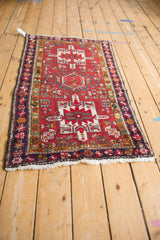 Vintage Persian Karaja rug viewed at an angle, displaying its triple geometric medallions and red field.