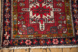 Corner detail of a vintage Karaja rug with a starburst palmette border in navy blue and saffron gold.