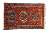 Vintage Persian Karaja rug with three geometric medallions on a red field and a starburst border.