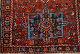 Corner detail of a vintage Karaja rug's blue geometric medallion and starburst motif border.