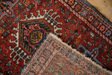 A folded corner of a vintage Karaja rug reveals the hand-knotted weave and cherry red pile.