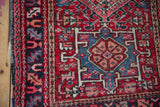 Intricate geometric blossoms and serrated leaves on vintage Karaja rug in red, navy, and beige.