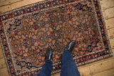 Feet on vintage Hamadan rug, showcasing Herati pattern, dusty blush, and subtle wear.