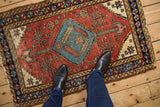 Antique Persian Heriz rug with a geometric medallion, shown on the floor for scale.