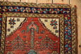 Corner of a collector's antique Persian Heriz rug showing the worn pile and geometric border.