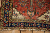 Geometric corner patterns and tattered end of an antique Heriz rug showing wear to the foundation.
