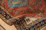 Folded corner on a fine antique Heriz rug revealing its ivory ground and geometric star blossom.