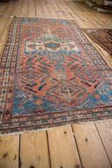 Vintage Malayer rug corner: dusty red field with Herati motif, worn blue spandrel, boteh borders.