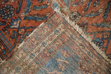 Vintage Malayer rug detail: worn brick red pile, tattered fringe, visible hand-knotted foundation.