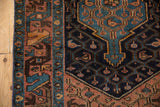 Vintage Hamadan rug showing dusty plum geometric border and navy blue field with even wear.