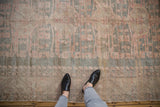 Distressed vintage Oushak rug showcasing faded slate blue and blush patterns with person's feet.