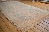Distressed vintage Oushak carpet featuring faded medallions and muted tones of beige, pink, and blue.