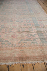 Angled close-up: distressed Oushak rug with muted beige, slate blue, pale rose.