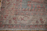 Corner view of distressed Oushak rug, fringed edge, serrated blue-red border, and aged pile.