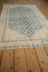 Vintage distressed Malayer rug displaying denim blue trellis and germinating plant pattern on an ivory field.
