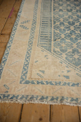 Detail of vintage Malayer rug, denim blue serrated leaf border on ivory, with distressed texture.
