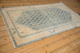 Distressed vintage Malayer rug corner, showing blue serrated leaf border, low pile, and fringe.